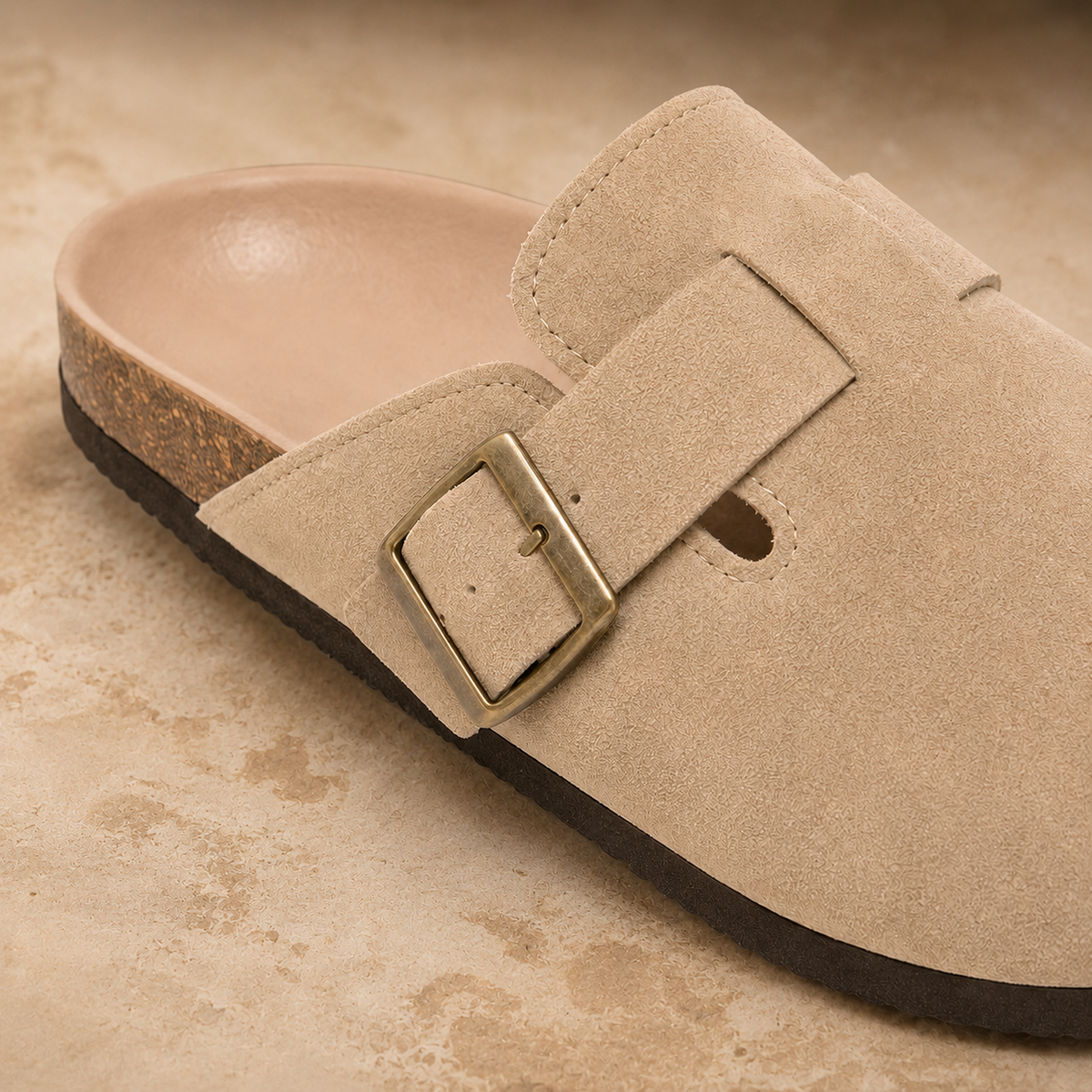 Close-up of the Marlow clog’s beige suede, antique-brass buckle, stitching and outsole edge.